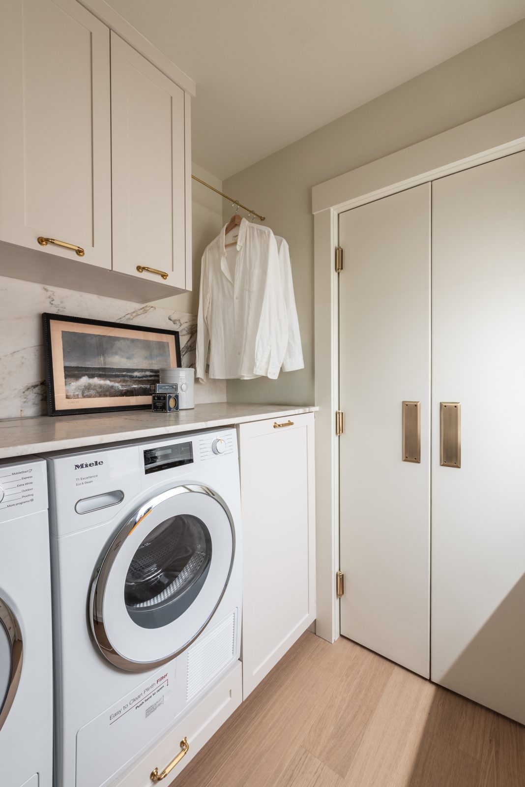 Modern Drift custom white laundry room cabinetry with painted shaker doors and full-height storage by Hempston Home