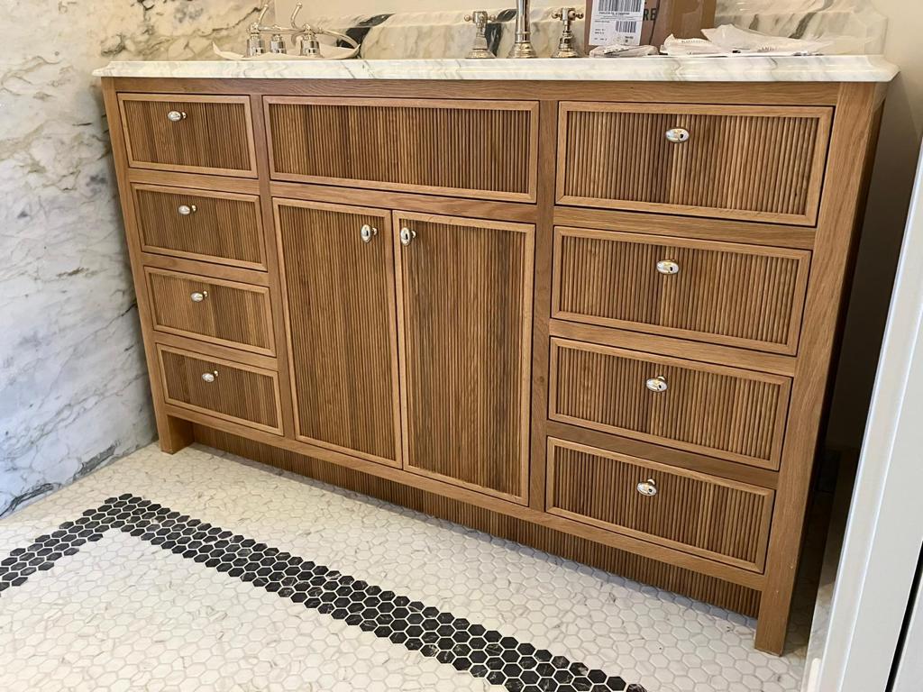 Reeded white oak vanity cabinetry with integrated storage and warm wood grain